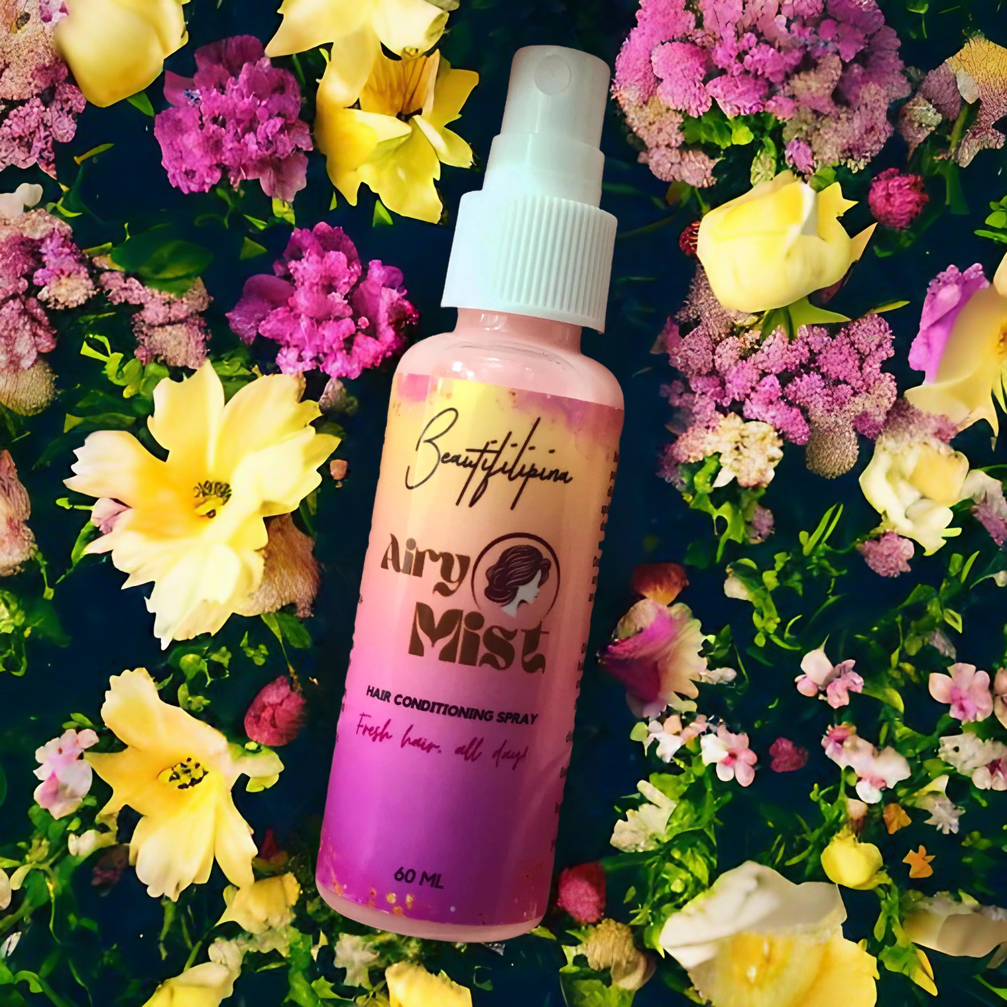 Beautifilipina Airy Mist hair conditioning and finishing spray travel size bottle laying on a bed of flowers